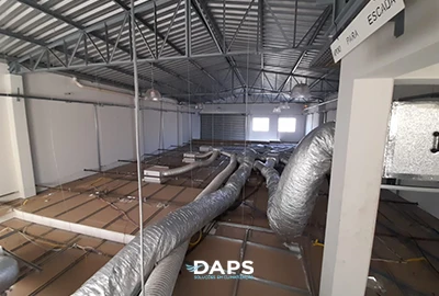 Rede de dutos de ar-condicionado instalada sobre o forro de um galpão, com canaletas e isolamento térmico executados pela DAPS Climatização em Campinas.