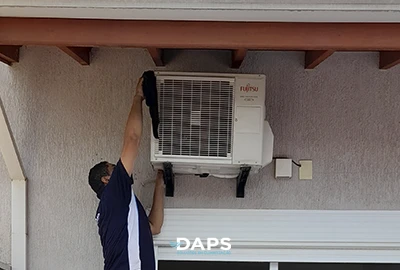 Técnico da DAPS Climatização realizando higienização da unidade condensadora de ar-condicionado split instalada na parte externa de residência em Campinas.