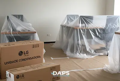 Sala preparada para instalação de ar-condicionado split LG, com móveis protegidos por plásticos e caixas das unidades condensadoras organizadas no piso pela DAPS Climatização.