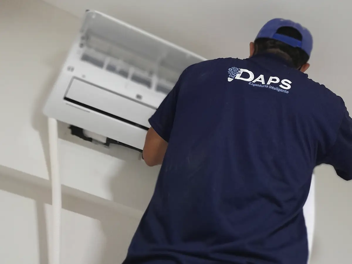 Técnico da DAPS Climatização realizando limpeza interna de ar-condicionado split em ambiente residencial, com a unidade evaporadora aberta para acesso à serpentina.