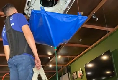 Técnicos da DAPS Climatização realizando limpeza de ar-condicionado split com capa de proteção, em ambiente interno em Campinas.