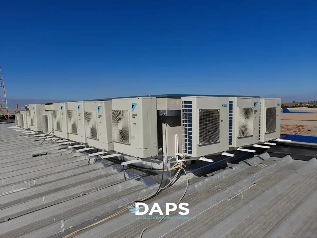 Múltiplas unidades externas de ar-condicionado tipo ART instaladas em linha em cobertura de edifício, demonstrando sistema de climatização de grande porte com conexões estruturadas, céu azul ao fundo.