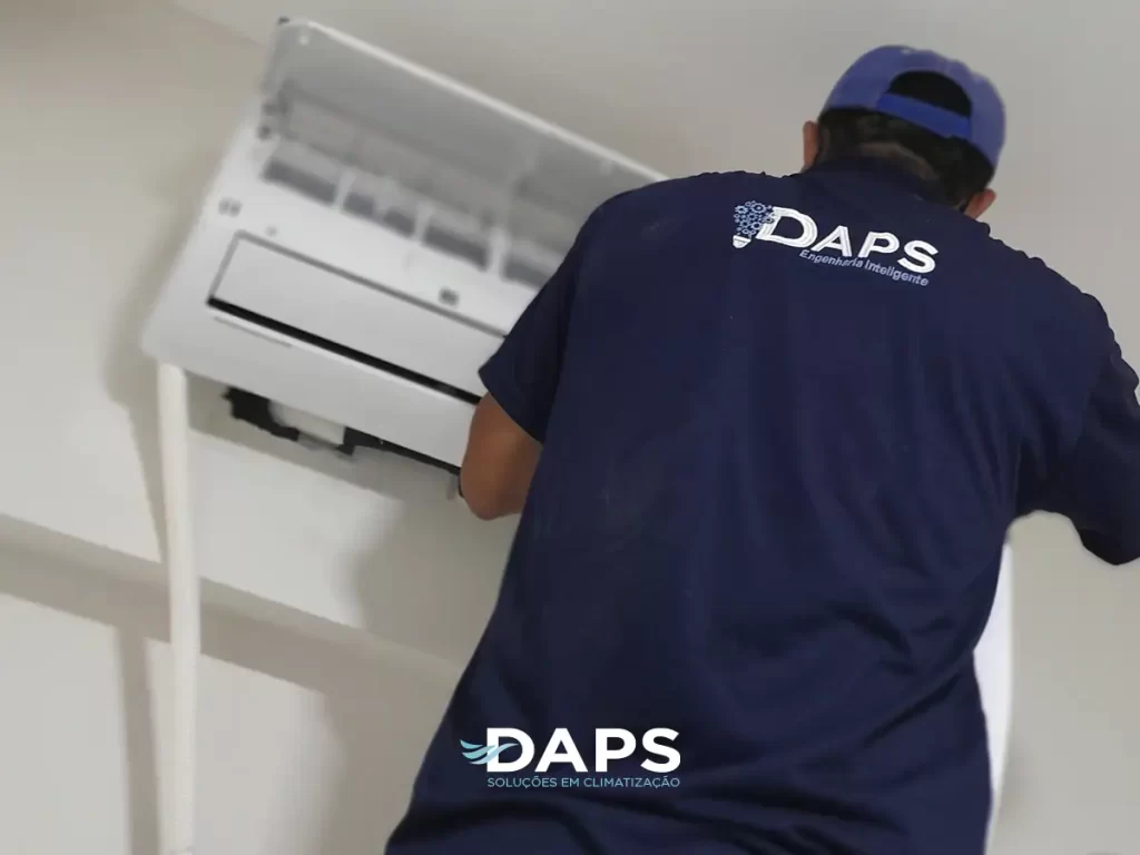 Técnico DAPS em uniforme realizando instalação de ar-condicionado tipo split de fácil instalação em parede branca de ambiente residencial, demonstrando procedimento técnico profissional.