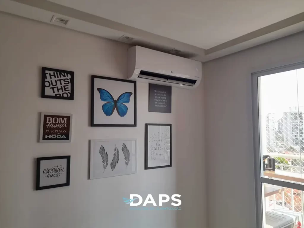 Sala de apartamento com ar-condicionado instalado na parede, decoração com quadros artísticos, janela com vista para a cidade e móveis modernos, demonstrando climatização em ambiente residencial decorado.