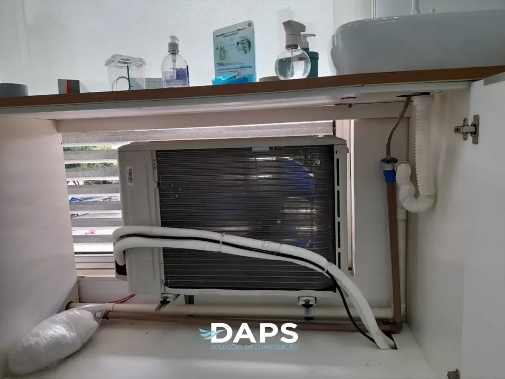 Unidade condensadora de ar-condicionado instalada em ambiente interno, mostrando estrutura interna com tubulações e componentes, conectores e suporte de fixação em Campinas.