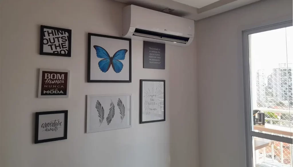 Ar-condicionado split instalado em sala de apartamento em Campinas, acima da parede decorada com quadros próximos à porta de acesso à sacada