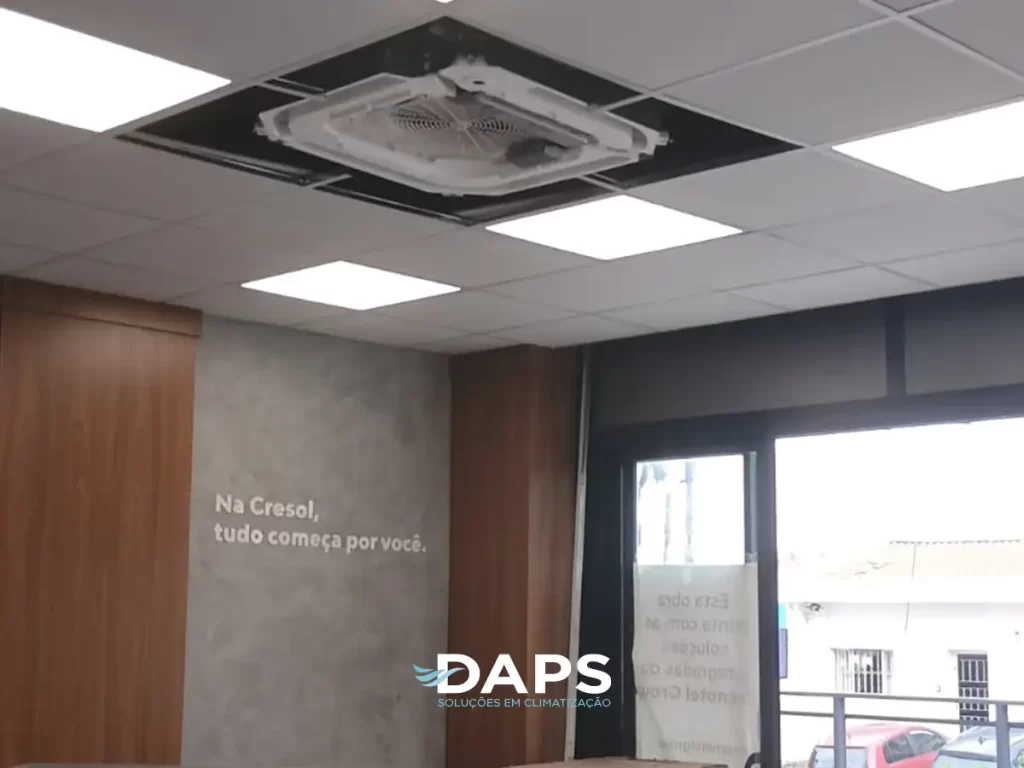 Sistema VRF (Refrigerante Variável) instalado em teto de gesso de ambiente comercial em Campinas, mostrando unidade cassete integrada com luminárias, vista para cidade através de vidraça.