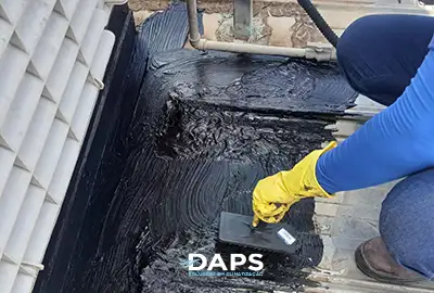 Técnico DAPS aplicando manta asfáltica para vedação na base de climatizador evaporativo em telhado